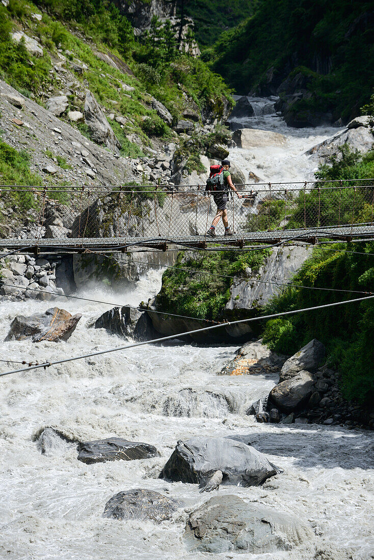 Young woman crossing the Marsyangdi river on the Annapurna Circuit Trek in the Marsyangdi valley, Nepal, Himalaya, Asia