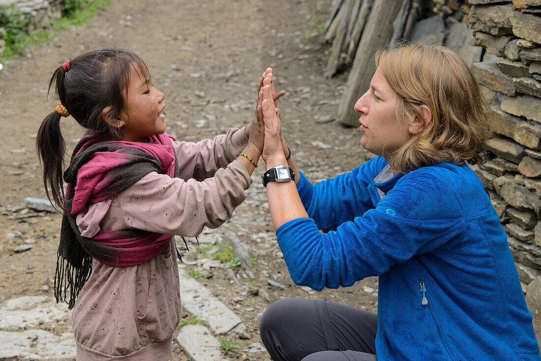 Young woman playing with a small girl in Nar on the Nar Phu Trek, Nepal, Himalaya, Asia