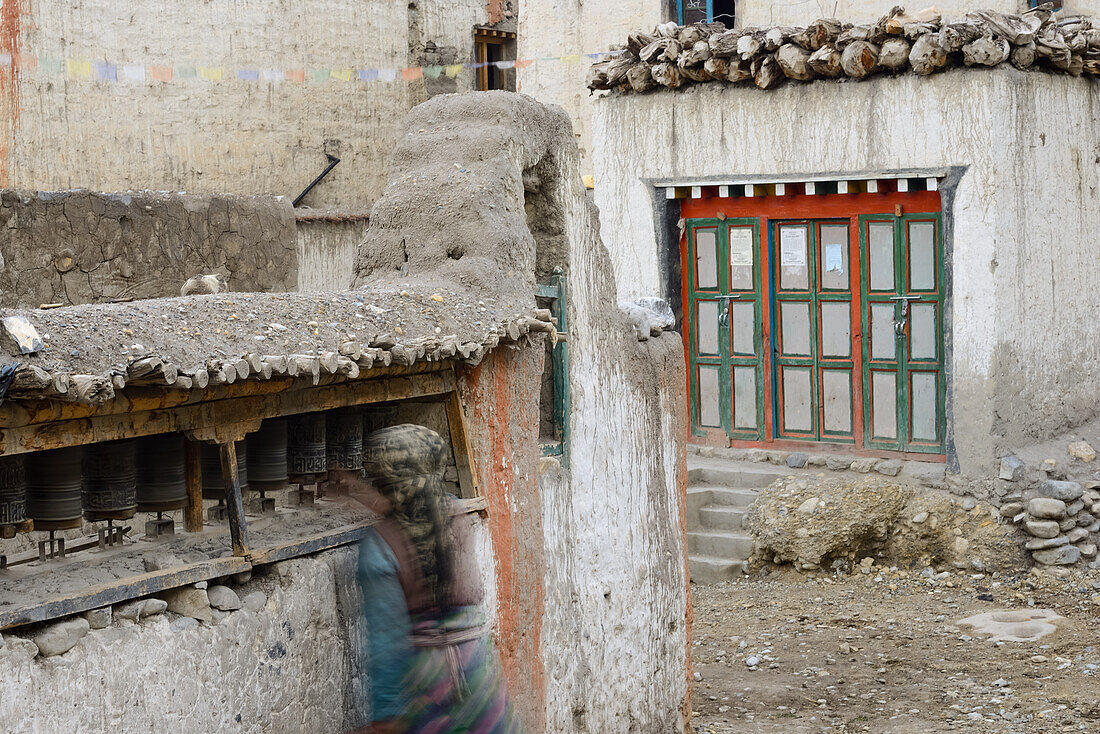 Woman turning the prayer wheels in Tangge, tibetian village with a buddhist Gompa in the Kali Gandaki valley, the deepest valley in the world, Mustang, Nepal, Himalaya, Asia