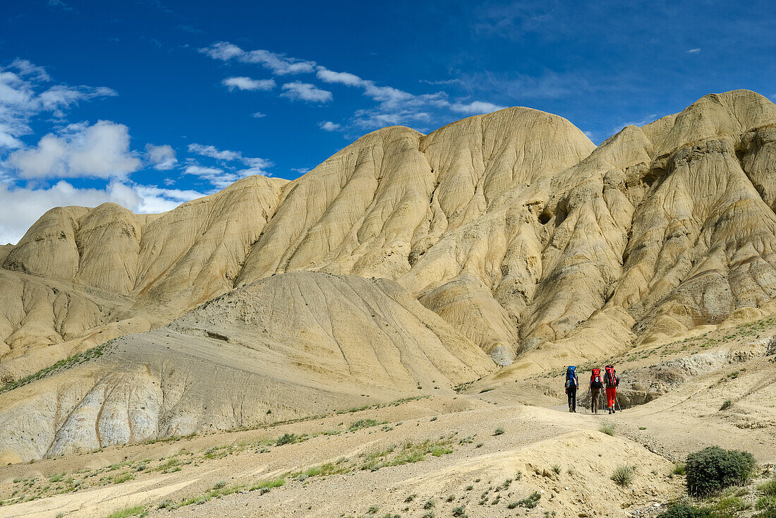 Drei Wanderer, Trekker in surrealer Landschaft typisch fuer das Mustang in der Hochwueste um das Kali Gandaki Tal, dem tiefsten Tal der Welt, Mustang, Nepal, Himalaya, Asien
