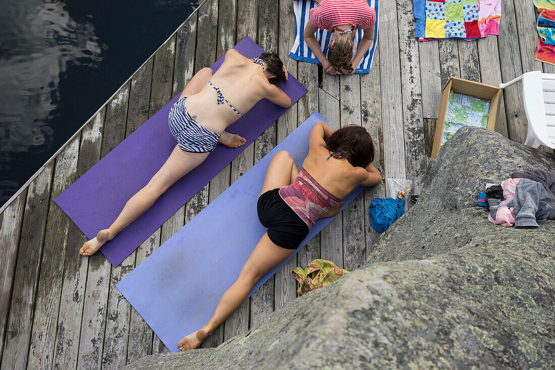 Women practicing yoga on wooden dock