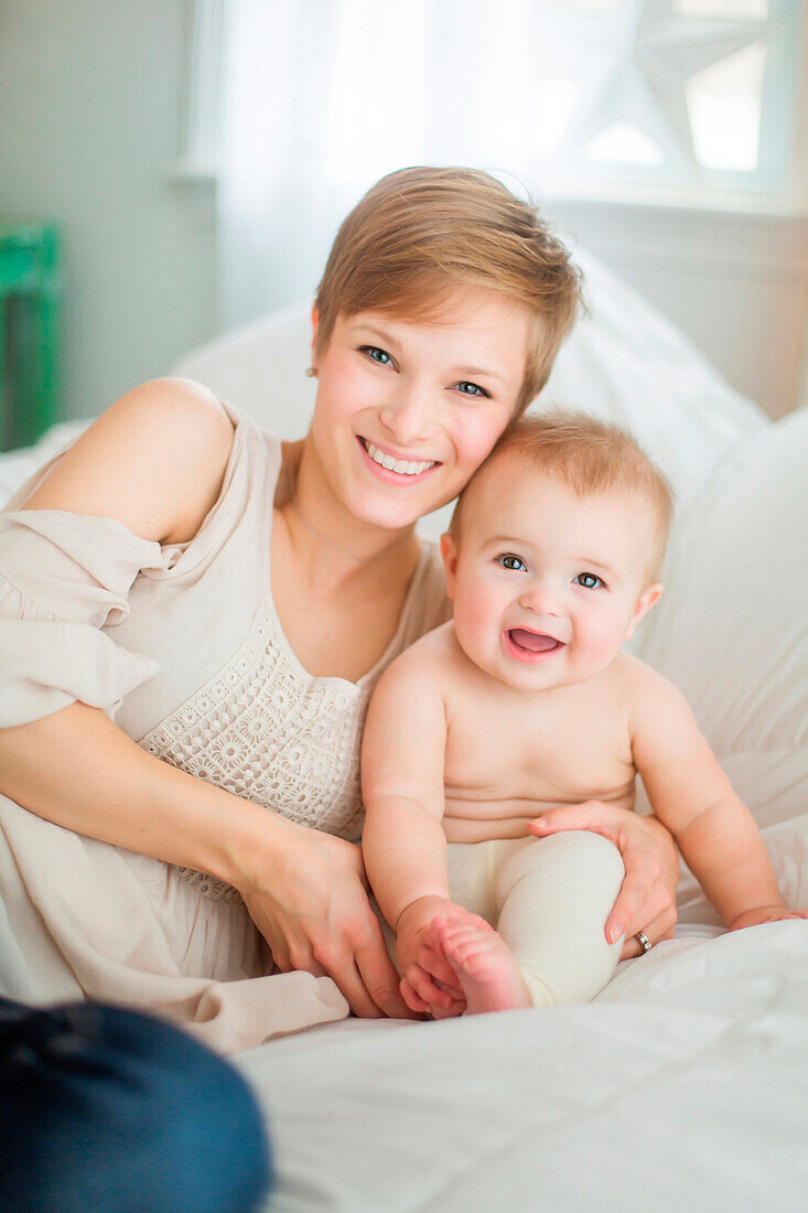 Caucasian mother and baby daughter smiling on bed
