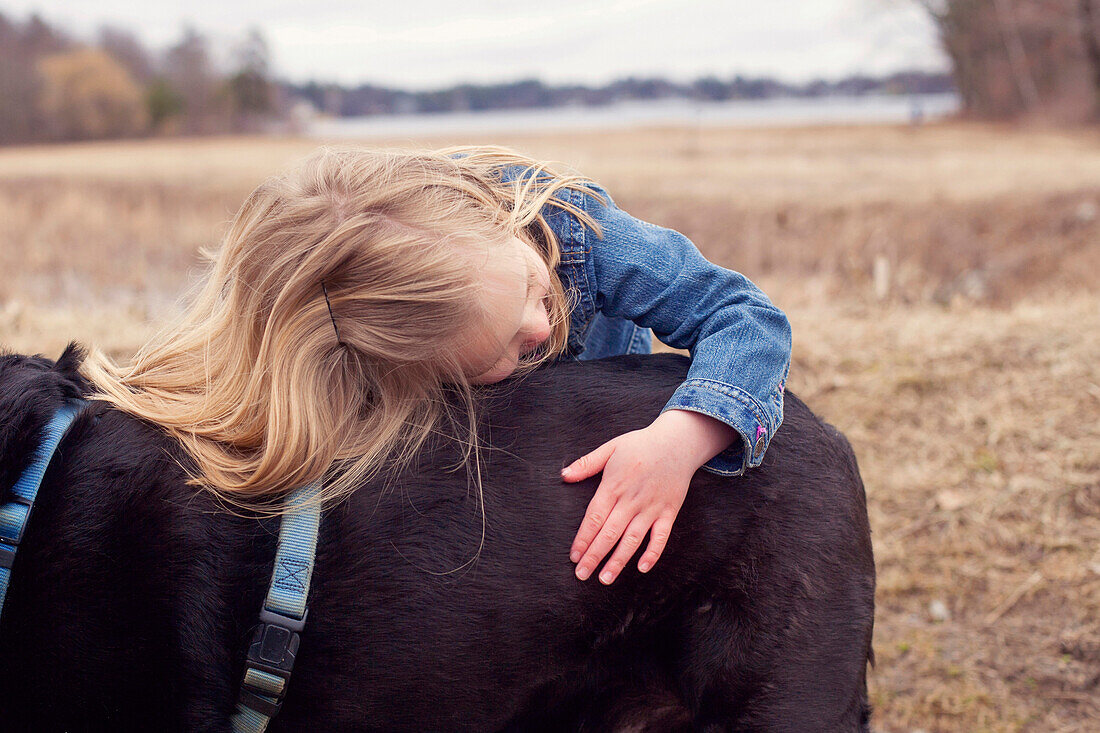 Close up of girl hugging dog in rural field