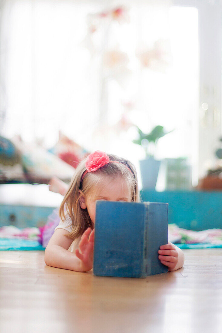 Girl reading book on living room floor