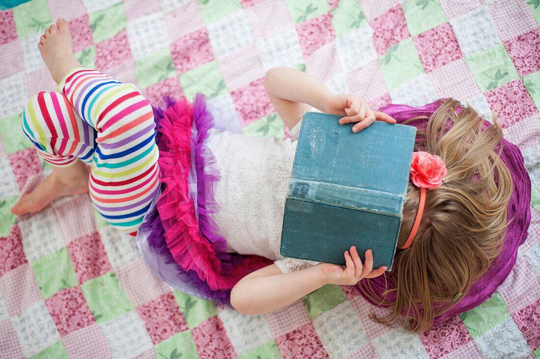 Girl reading book on blanket