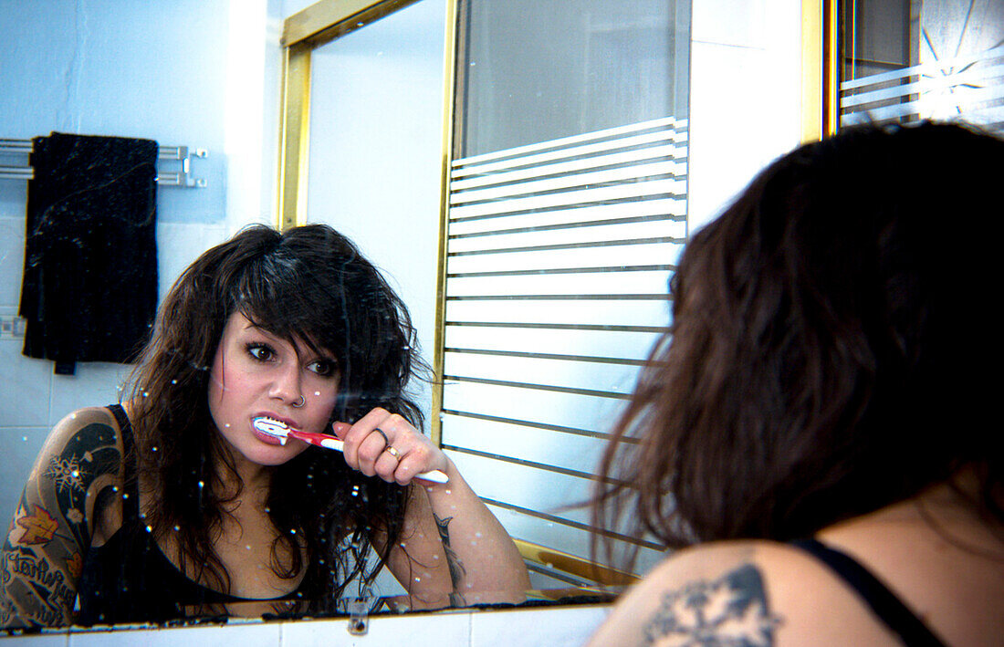 Kaukasische Frau putzt sich die Zähne im Badezimmerspiegel