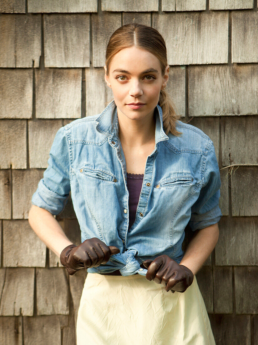 Woman tying her shirt near wooden shingles