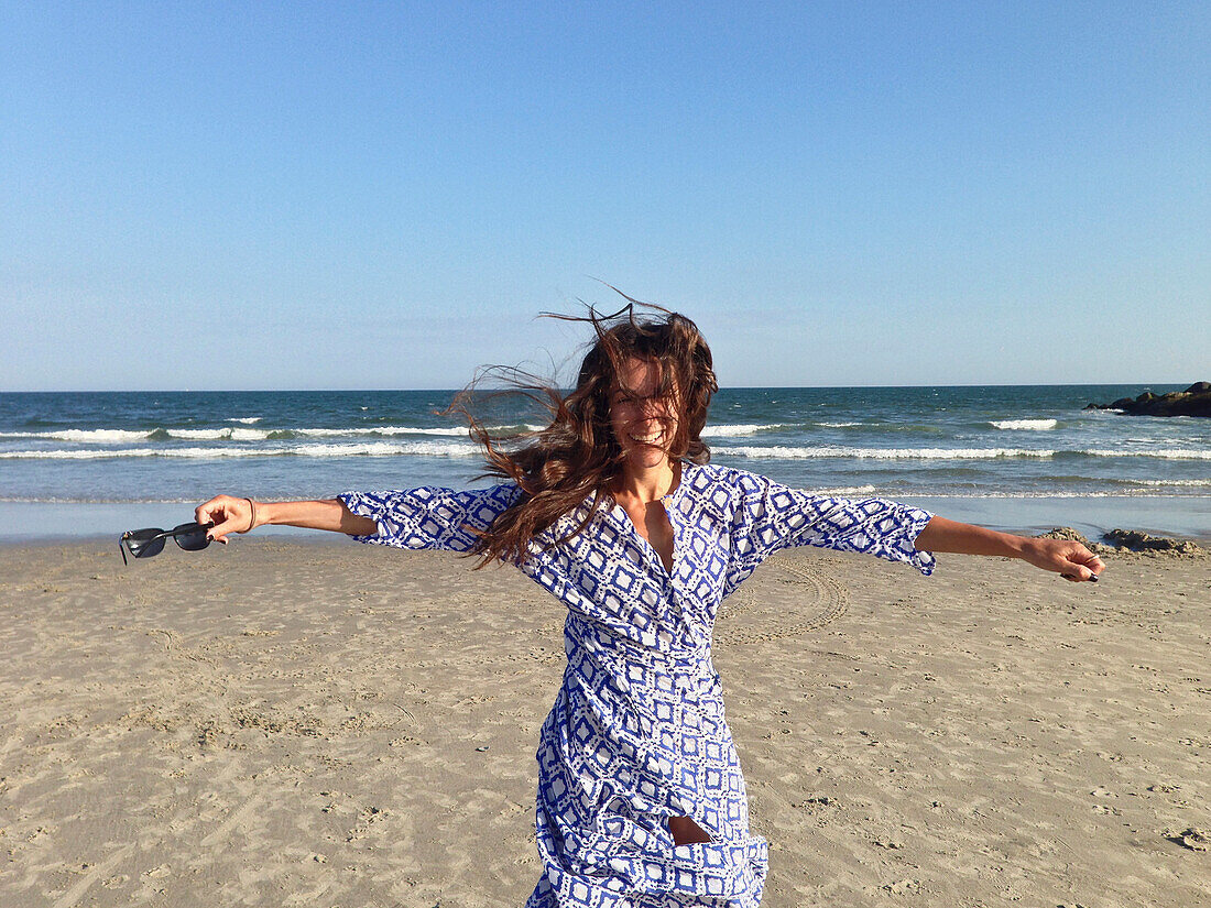Smiling woman with arms outstretched on beach