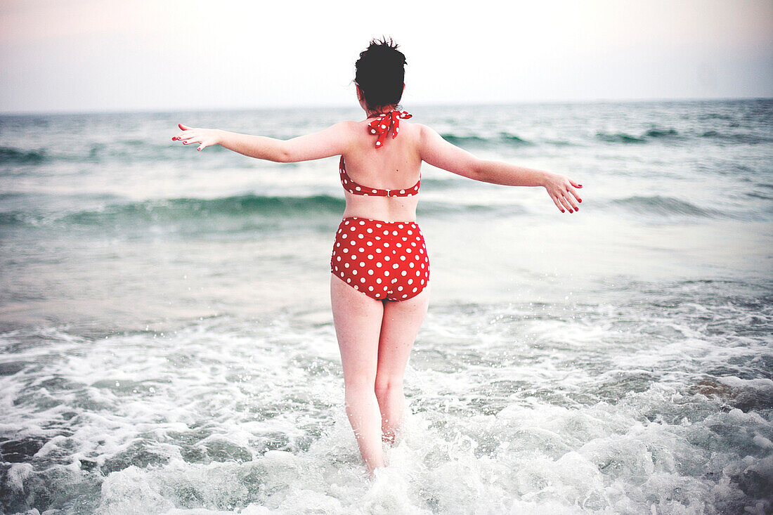 Caucasian teenage girl splashing in ocean waves