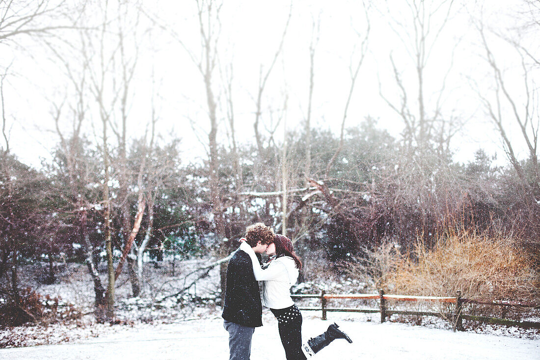 Couple kissing in snowy rural field