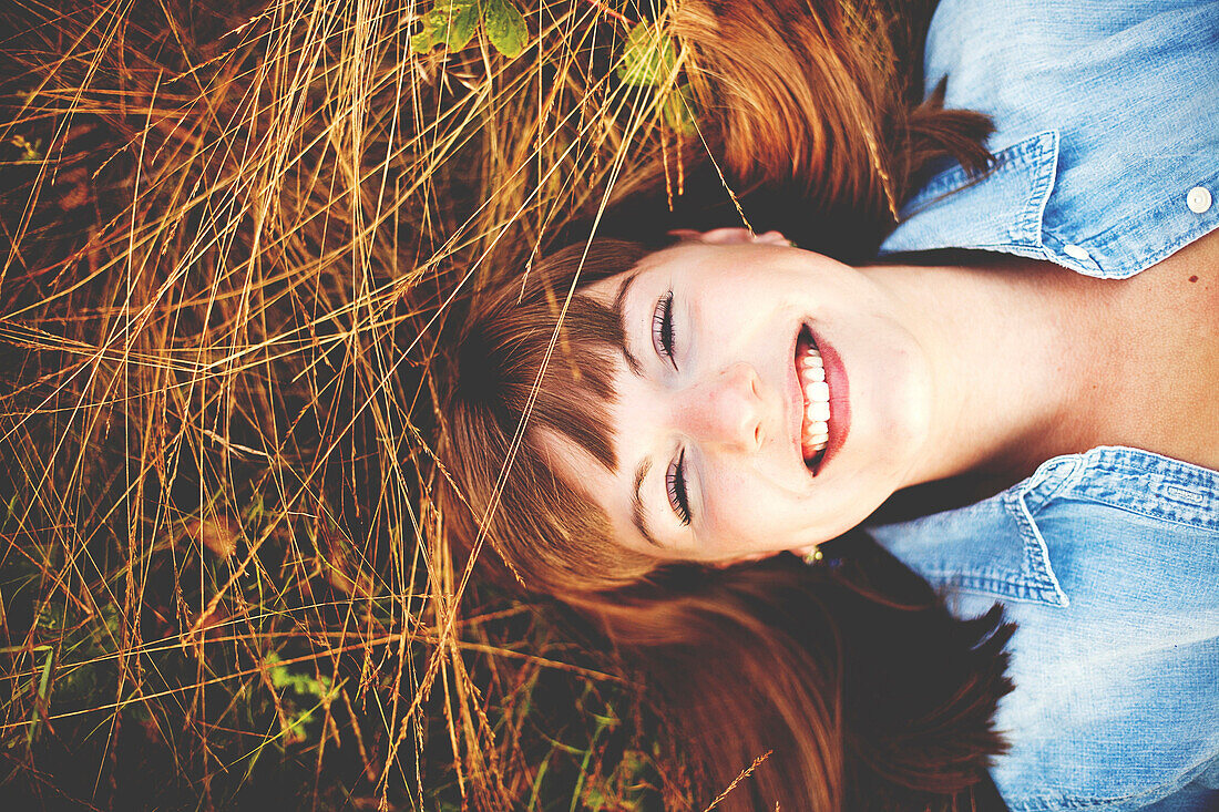 Close up of smiling woman laying in tall grass