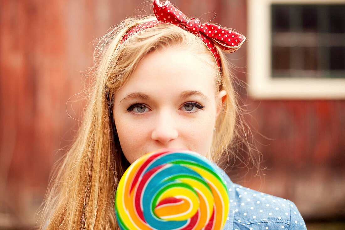 Caucasian teenage girl licking lollipop