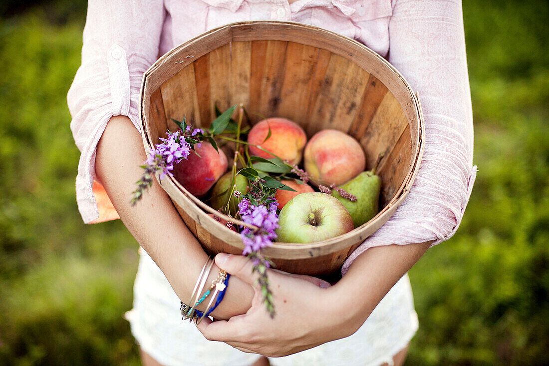 Frau trägt Eimer mit Äpfeln auf einem Feld