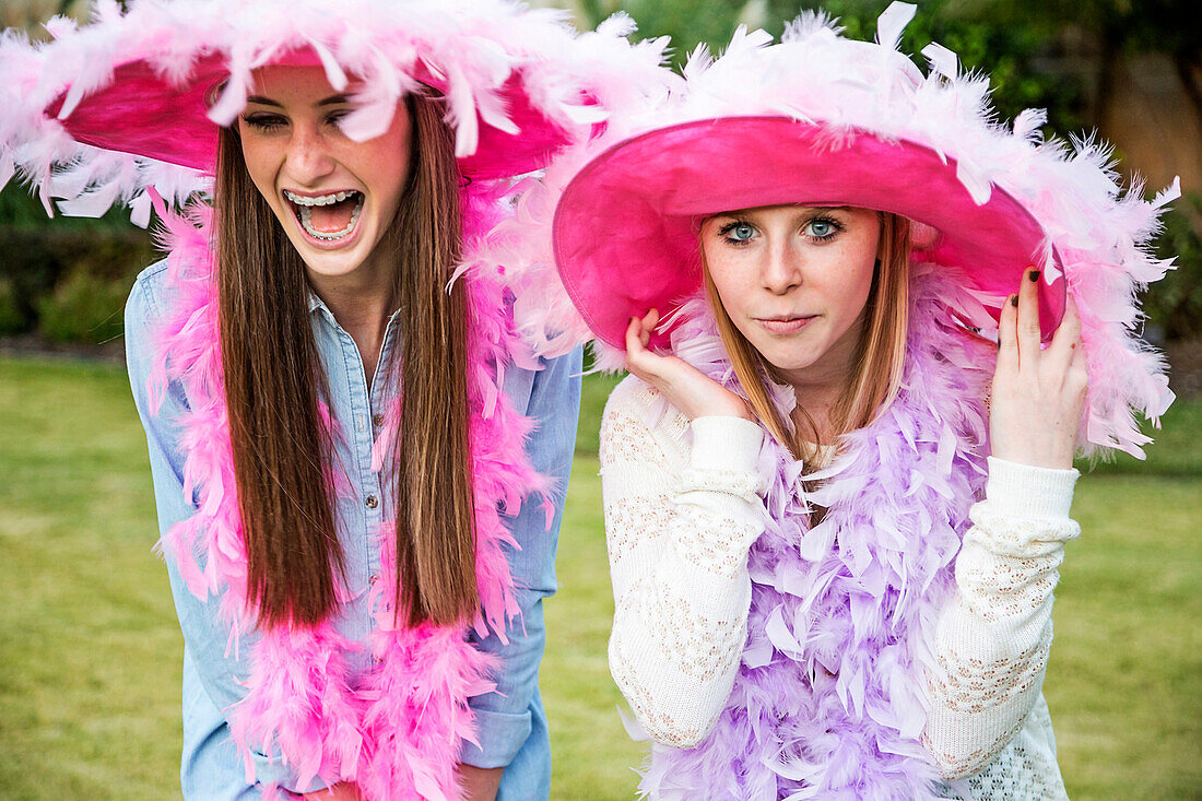 Caucasian teenage girls wearing feather boas and hats