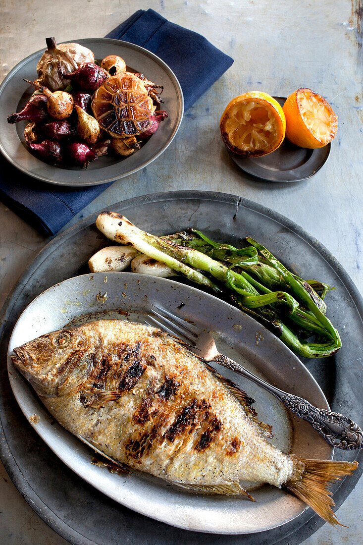 Plates of grilled fish, vegetables and garlic