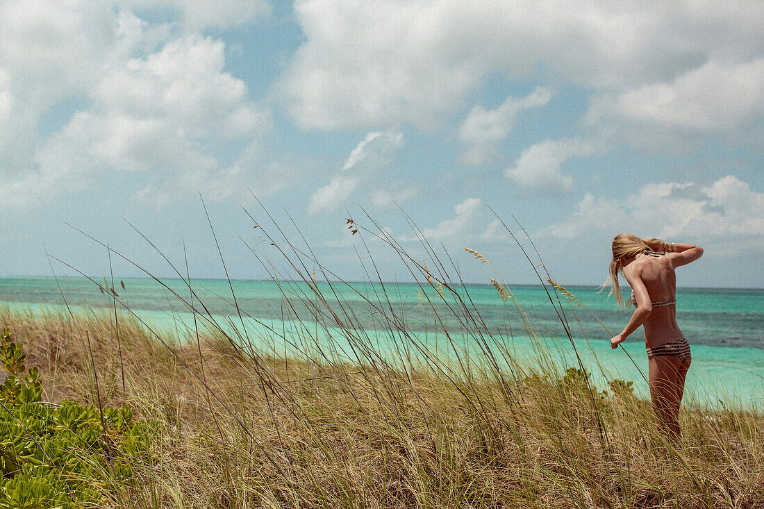 Woman in bikini standing in beach grass