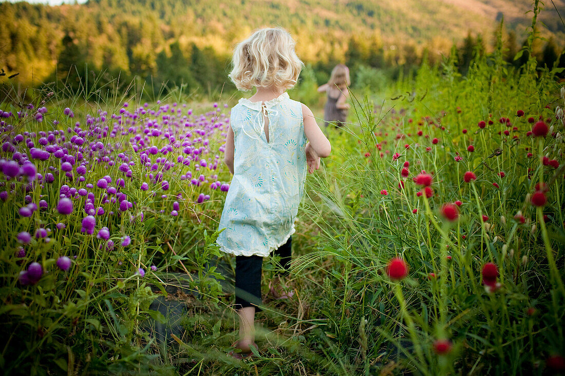 Mädchen, das in einem ländlichen Blumenfeld spazieren geht