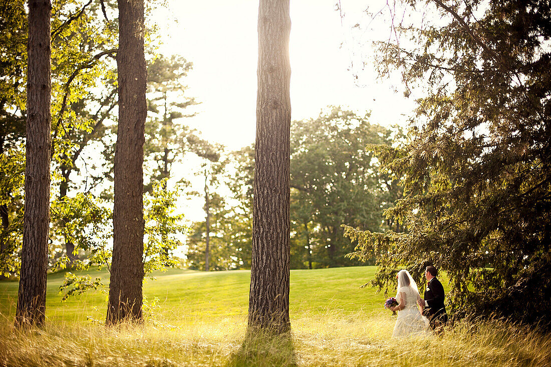 Bride and groom walking in rural field