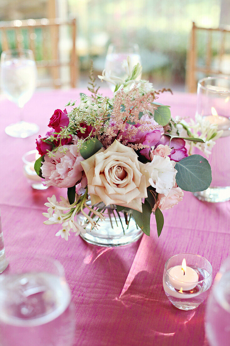 Blumenstrauß in Vase auf rosa Tischtuch