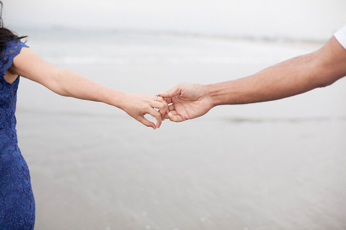 Close up of couple holding hands on beach