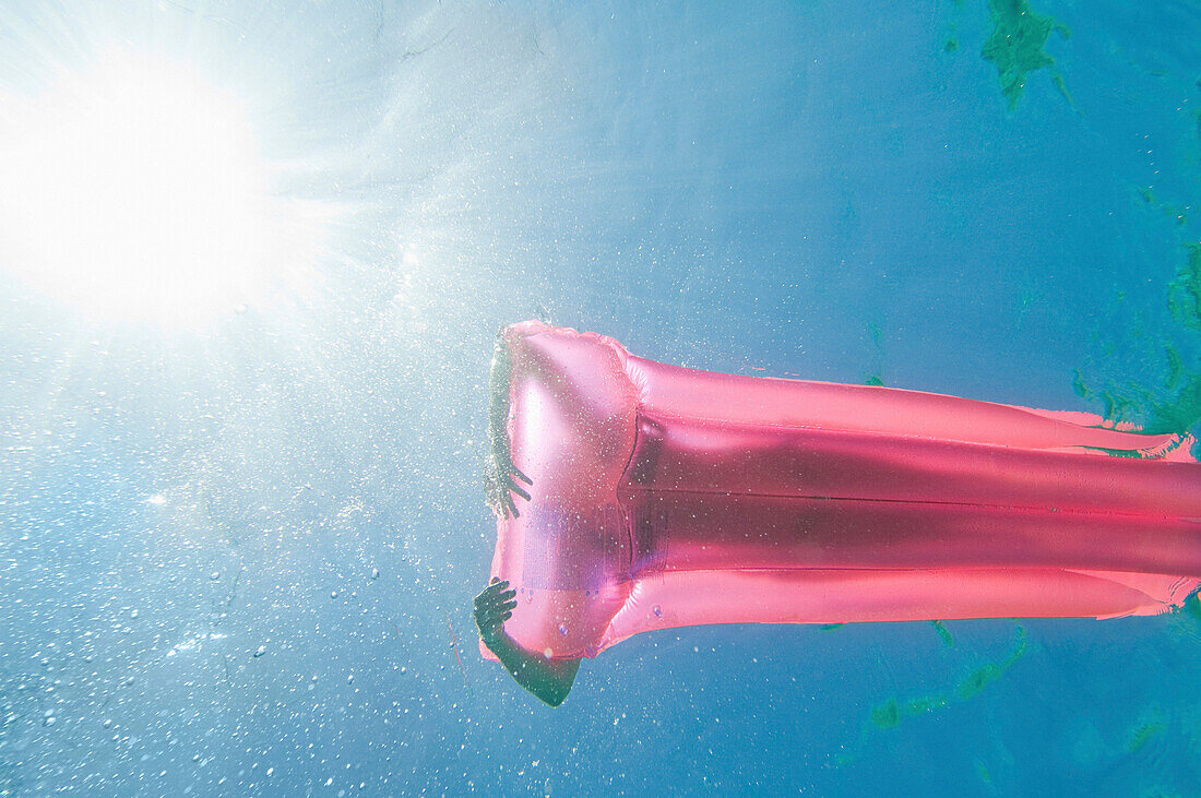 Underwater view of woman sunbathing on raft in ocean