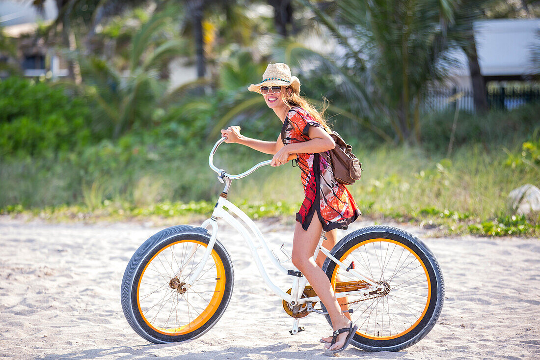 Hispanic woman riding bicycle on beach