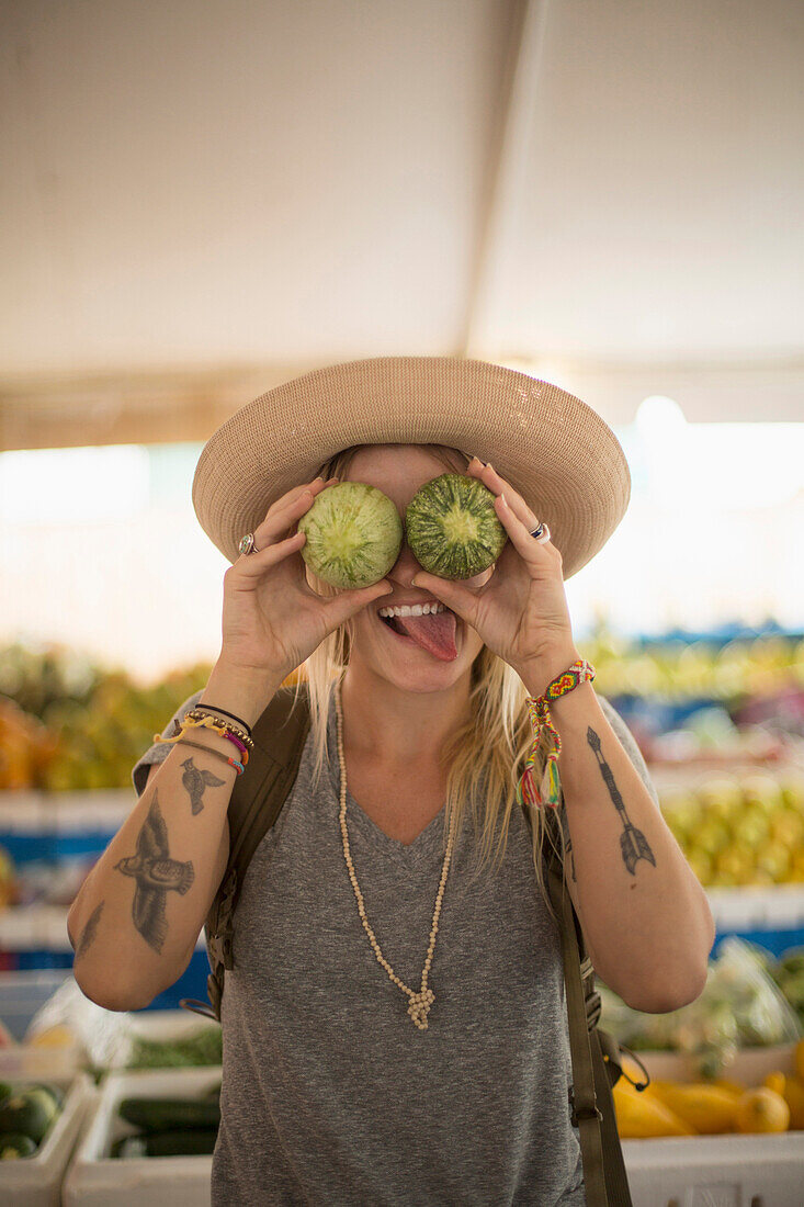 Caucasian woman making a face with fruit in farmers market