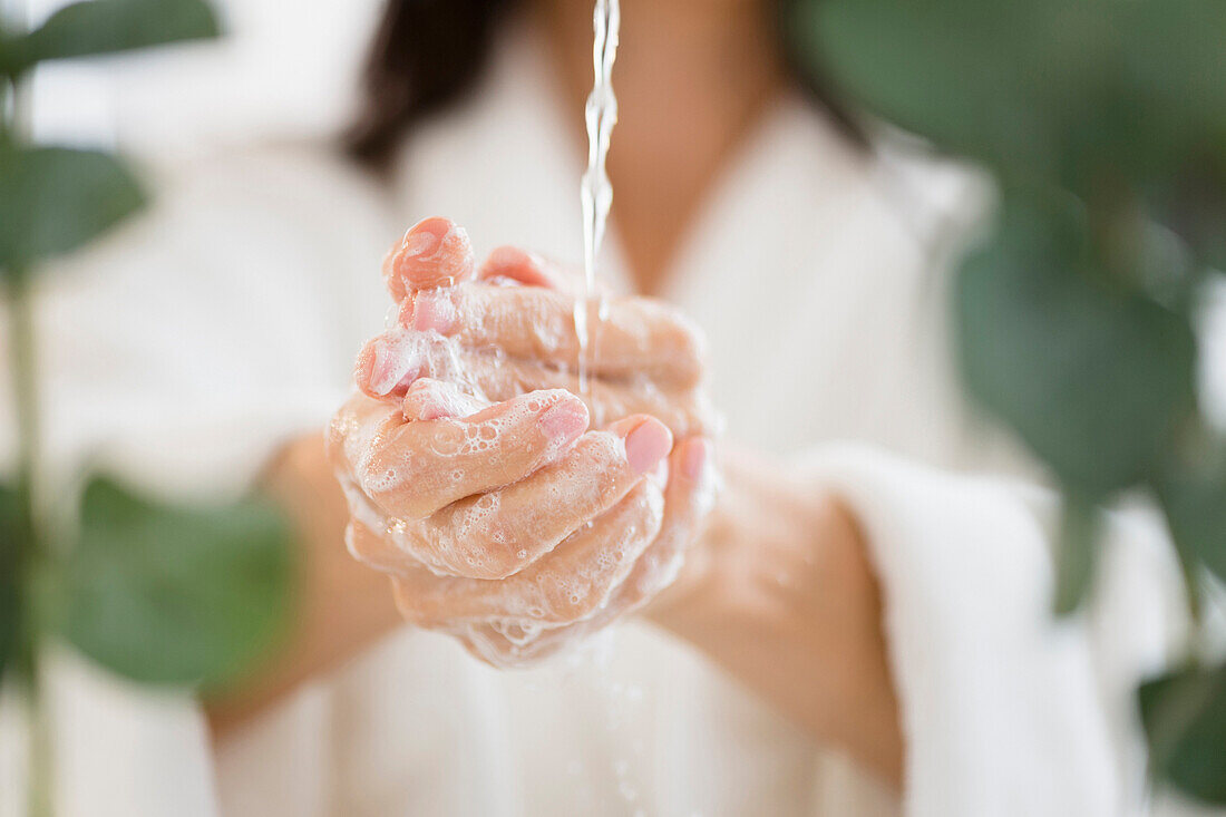 Gemischtrassige Frau wäscht sich die Hände im Wasser