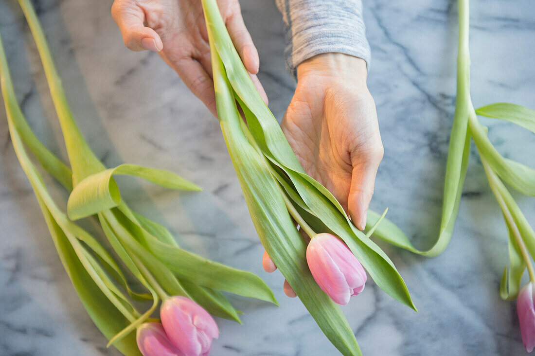 Gemischtrassige Frau hält Tulpen am Tisch