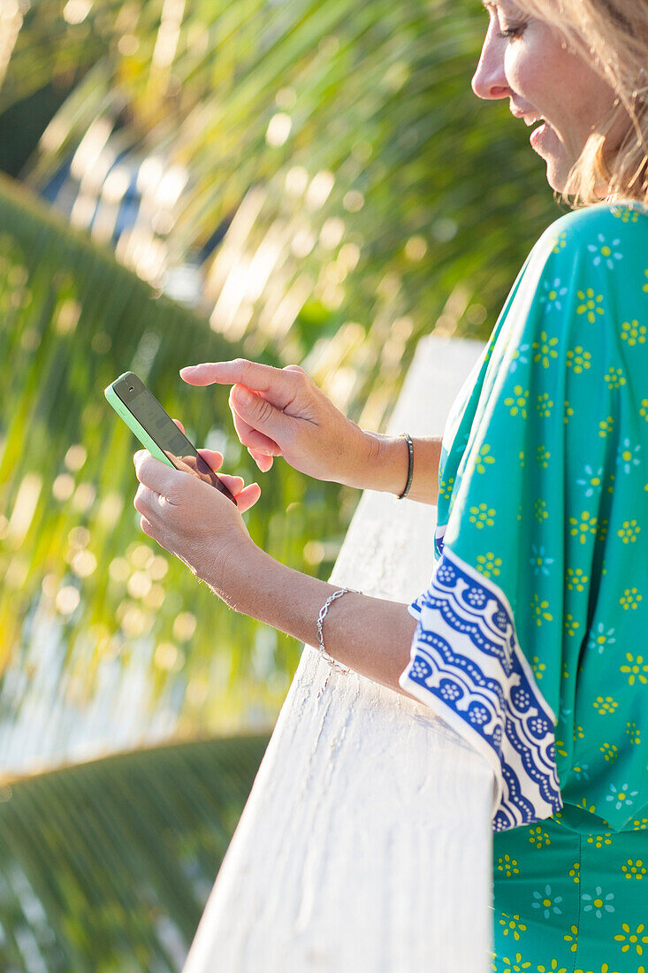 Hispanic woman using cell phone on patio