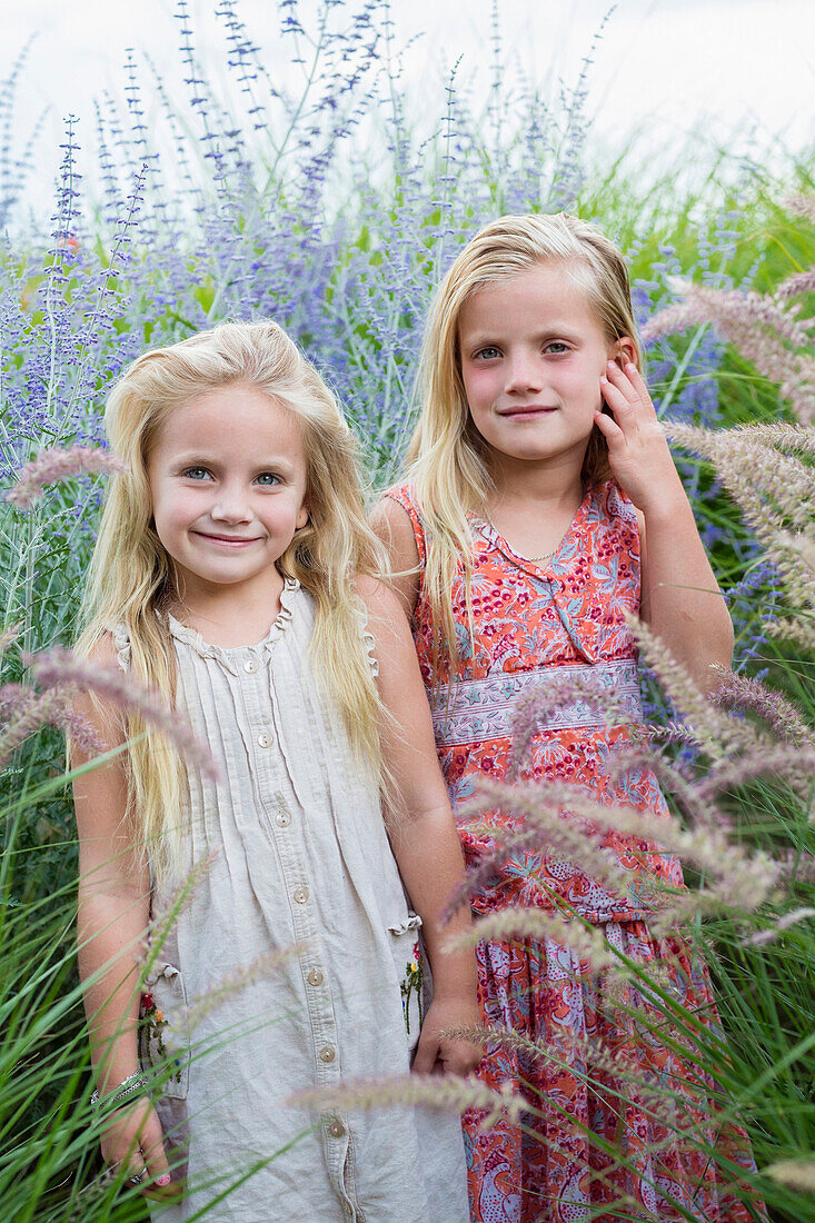 Caucasian sisters standing in tall grass