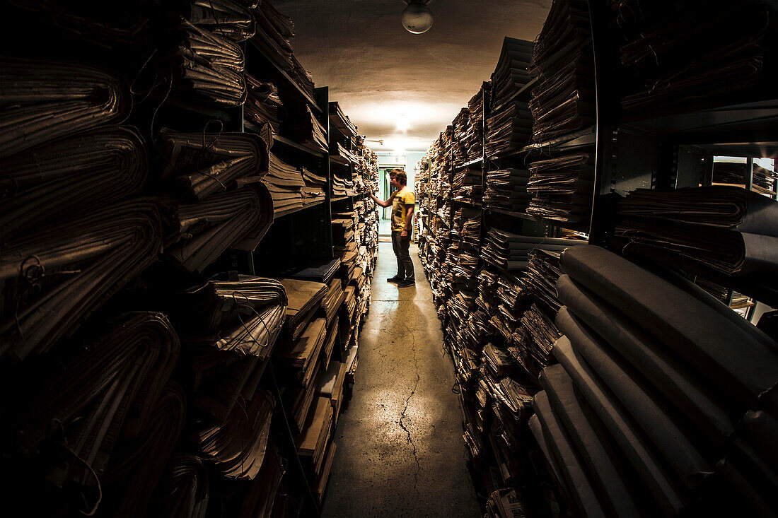 Caucasian man searching old newspapers in library archive