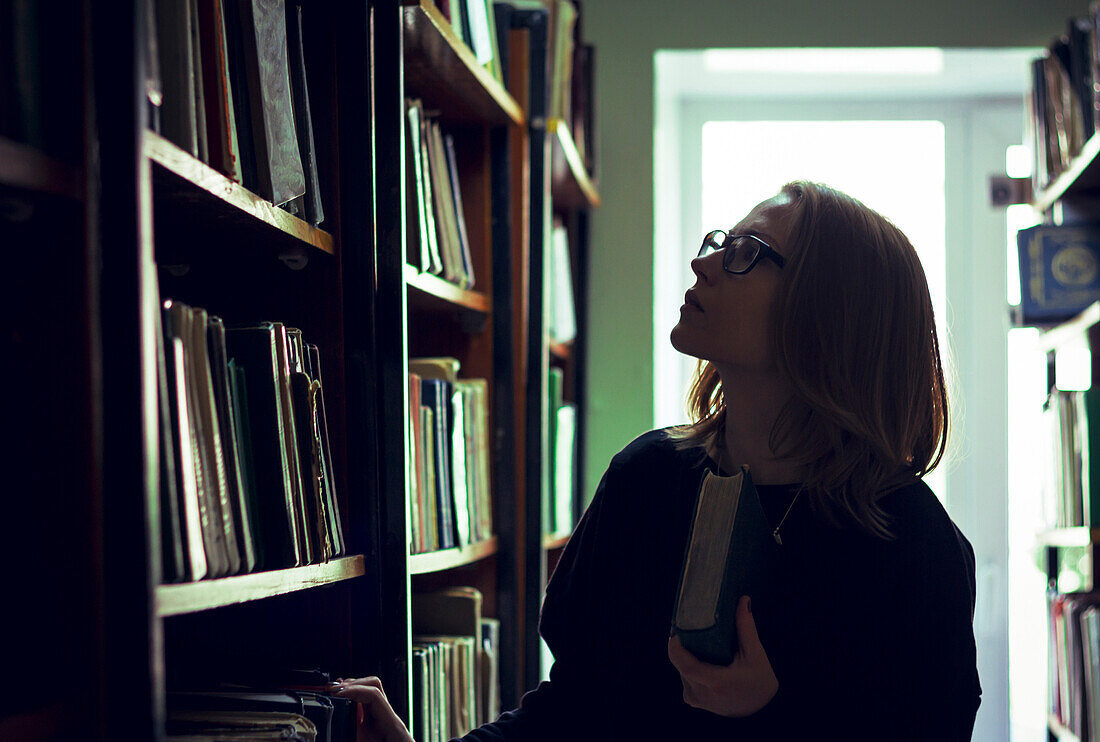 Caucasian woman searching for book in library