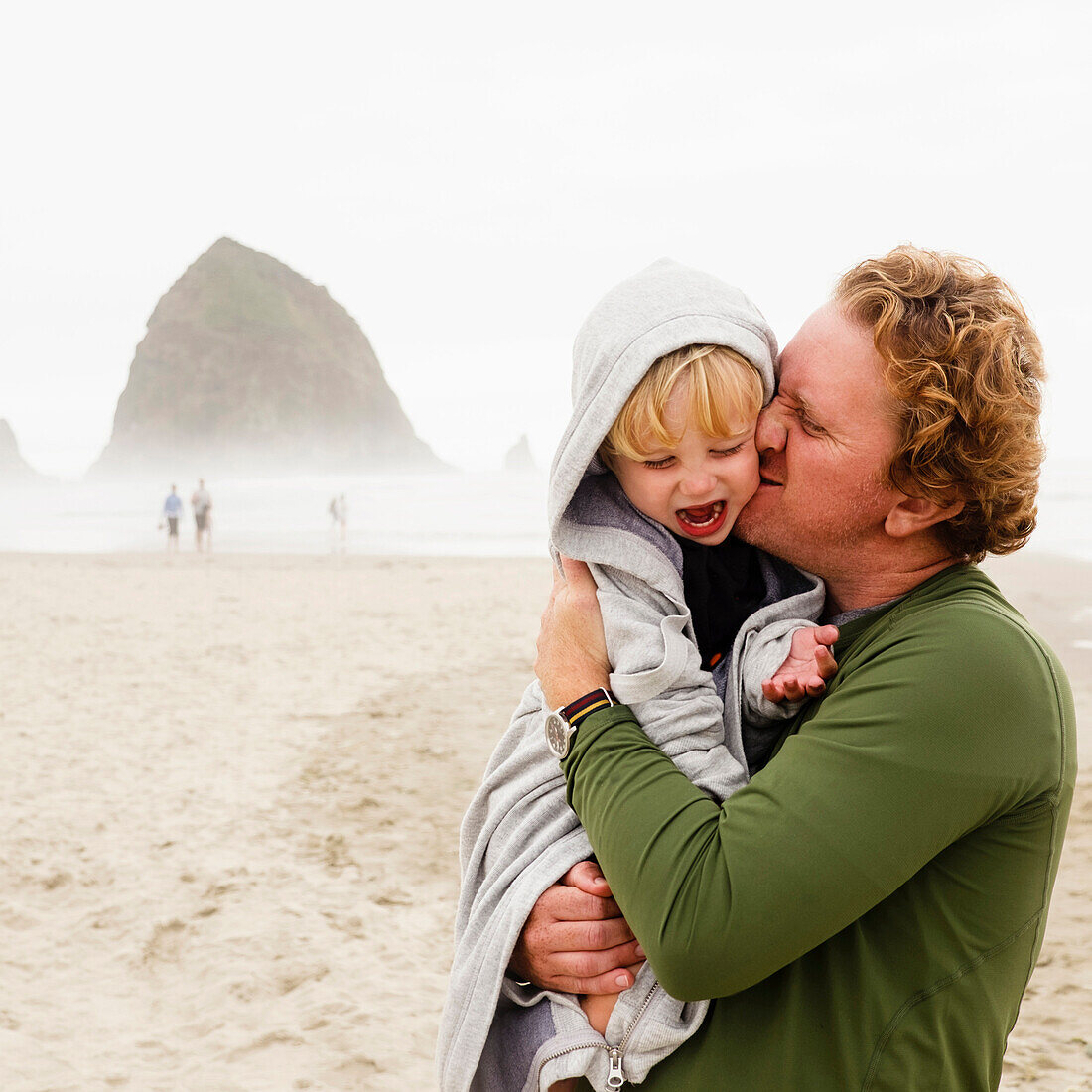 Caucasian father kissing son on beach