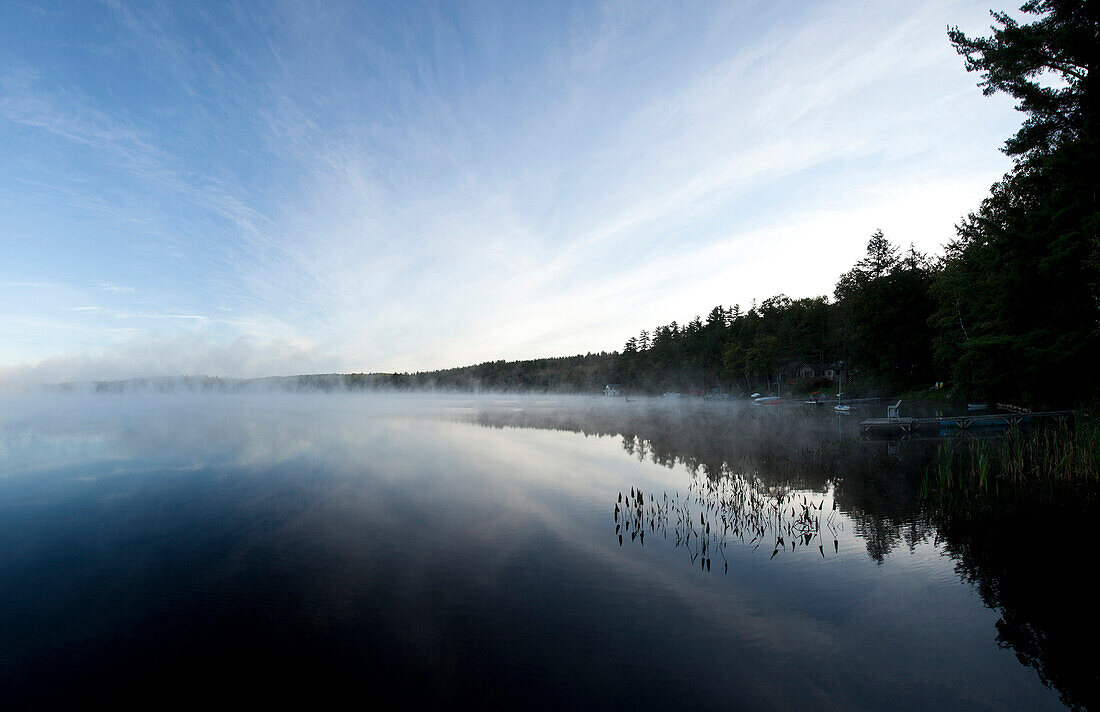 Mist clouds over still lake in remote landscape