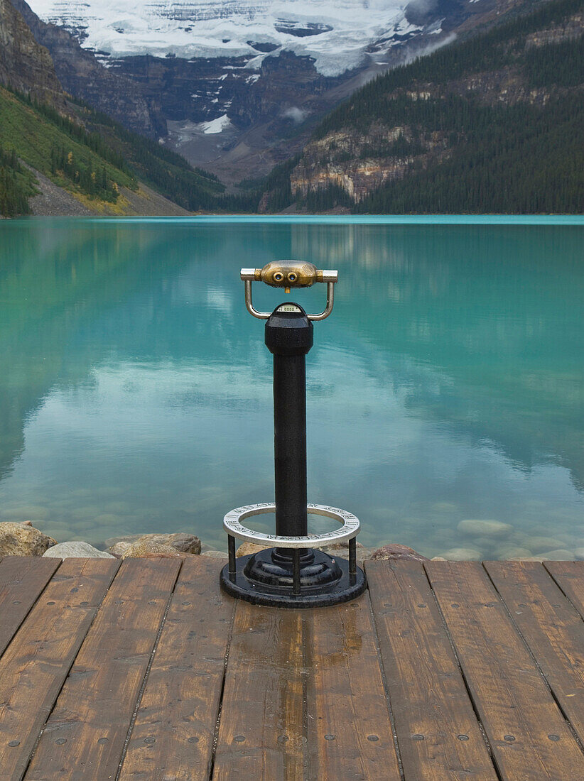 Binoculars overlooking still lake in rural landscape