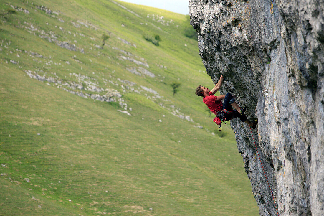 A climber scales a limestone cliff in Upper Wharfedale, Yorkshire Dales National Park, Yorkshire, England, United Kingdom, Europe