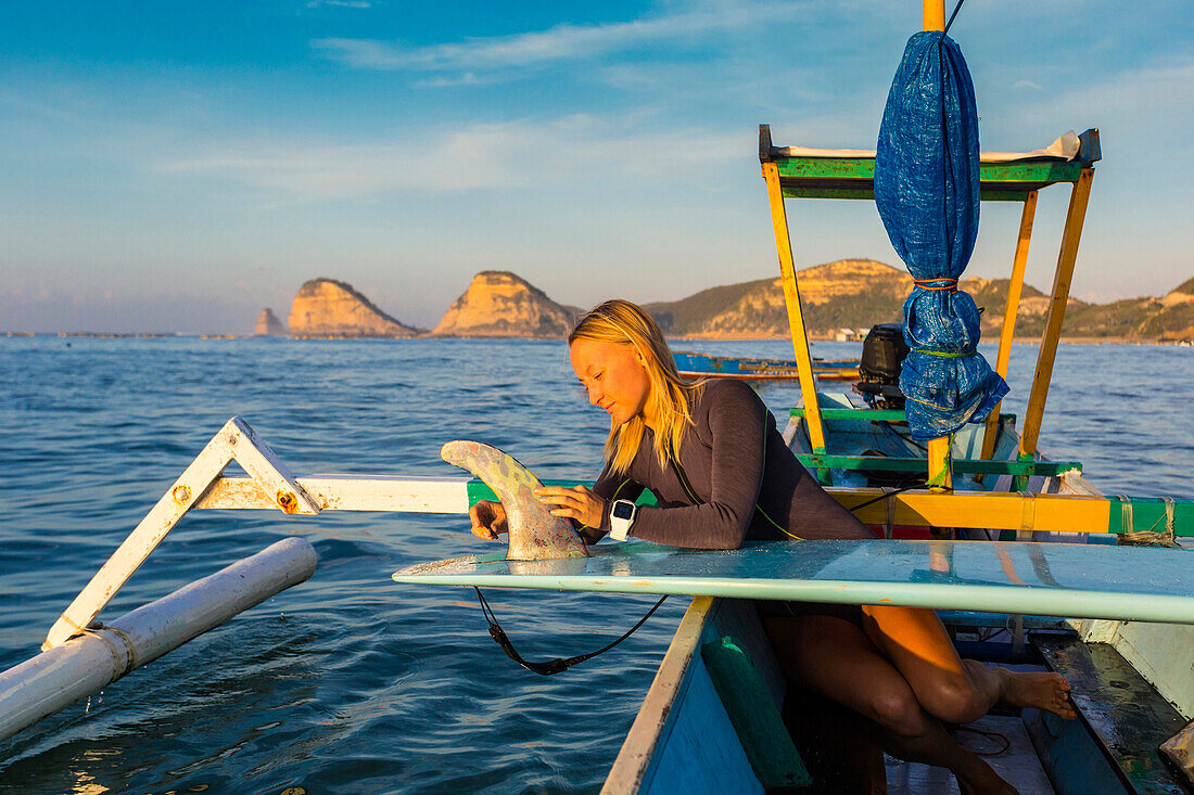 Young surfer girl in an old boat.