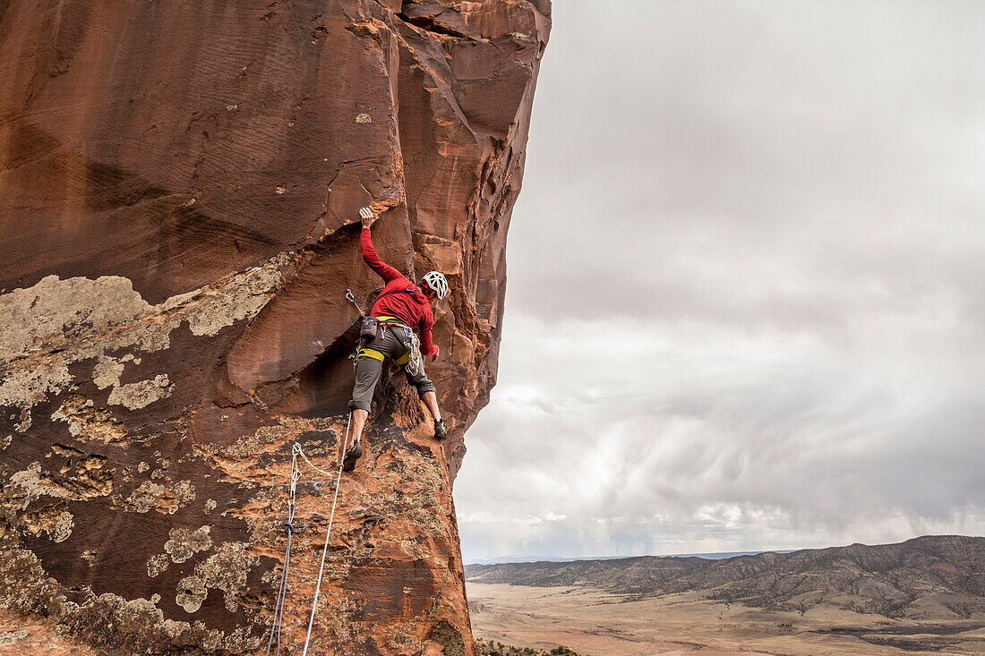 A man rock climbing a desert sandstone tower called Psycho Babble Tower in the Big Gypsum Valley near, Naturita, Colorado.
