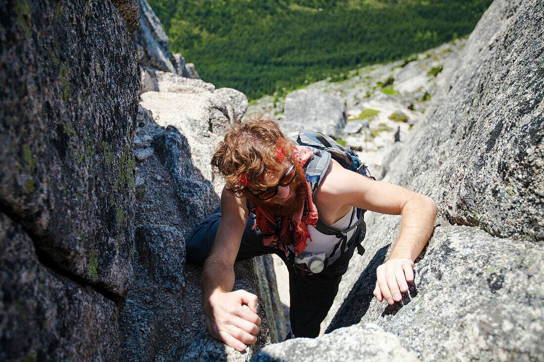 Evan Howard, a climber and explorer, climbs up a granite rock chimney en route Needle Peak  in British Columbia, Canada.