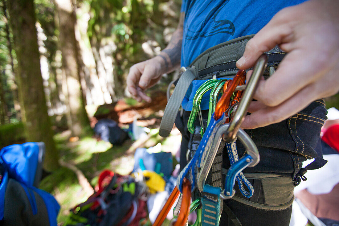 A rock climber clips in a carabiner quickdraw on to his harness.