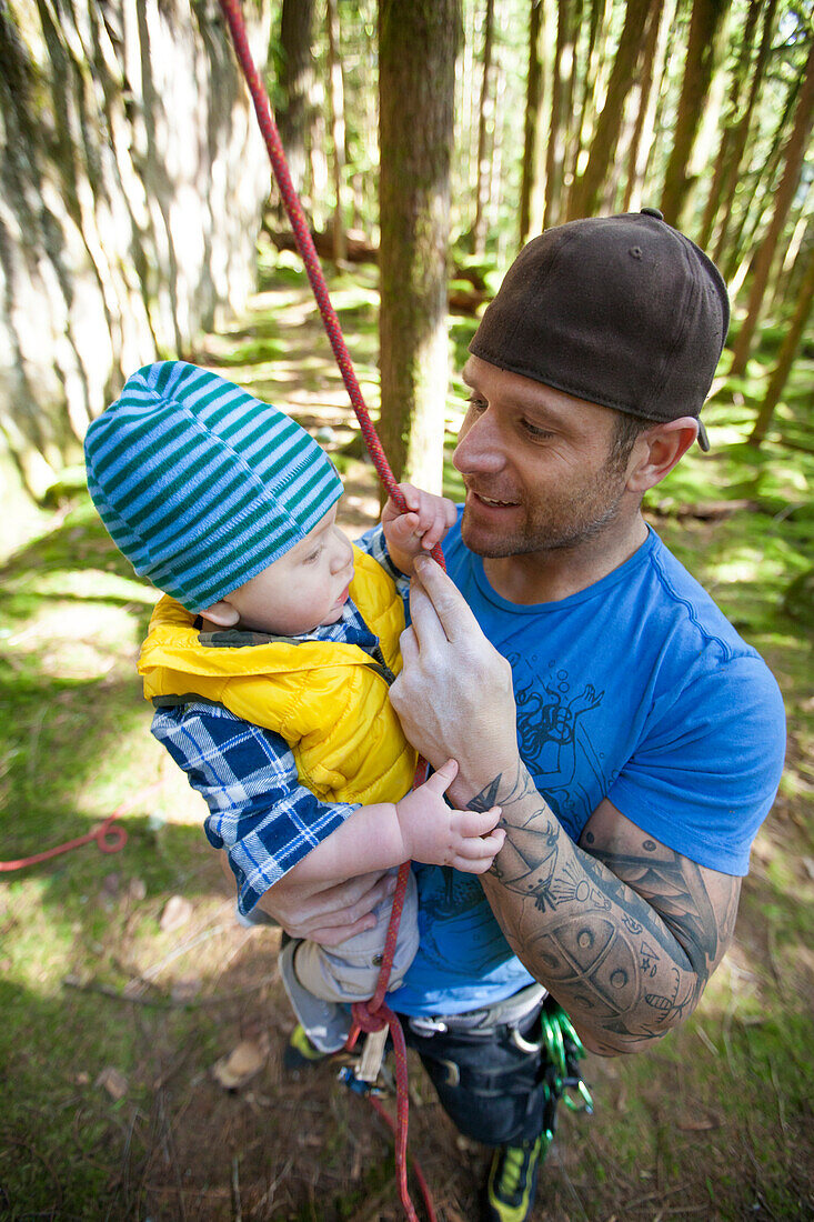 A man holds his son before rock climbing.