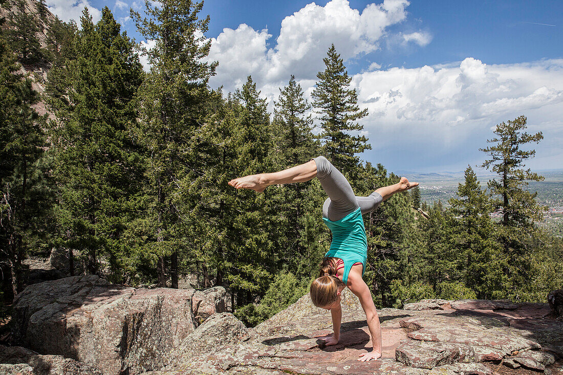 Flexible and strong female holds a hand stand on the rocks in Boulder, Colorado