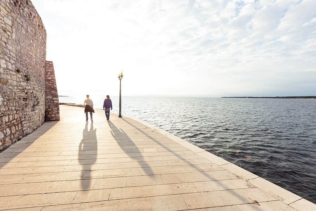 Two men walking along the waterfront of Porec, Istria, Croatia