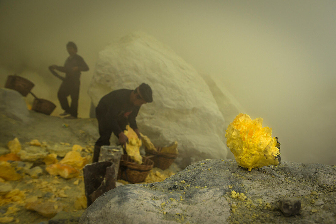 Miners of the devil mine of Ijen volcano loading transport baskets with sulfur - Indonesia, Java