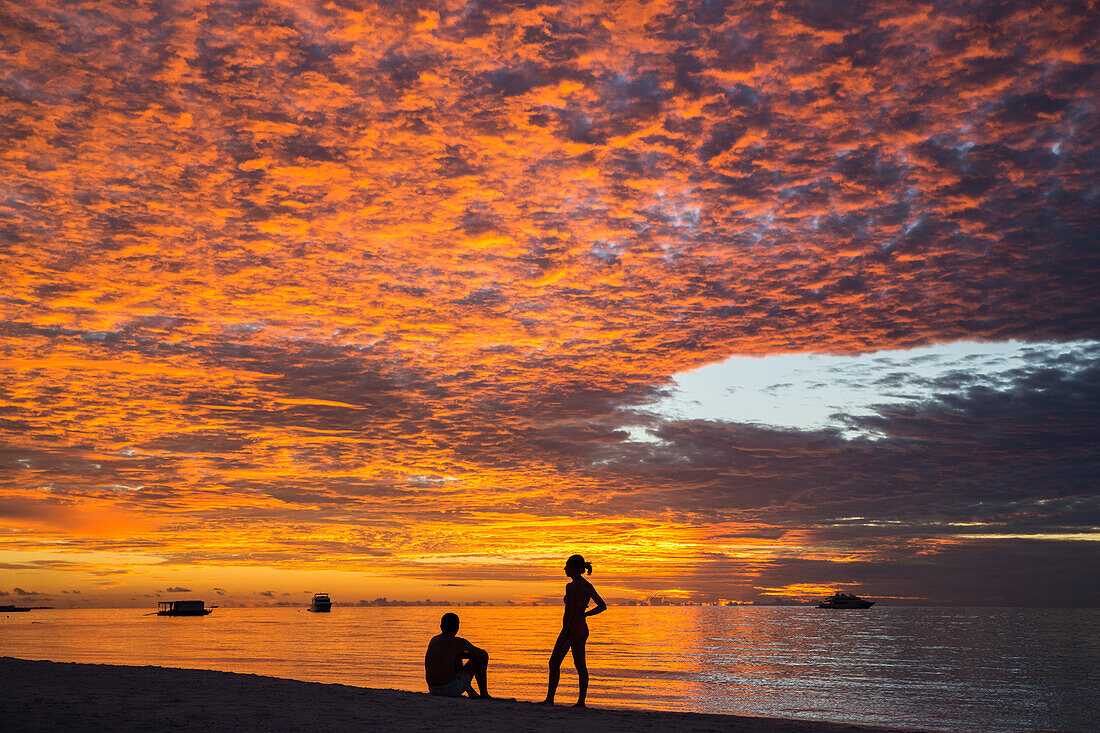 Sonnuntergang mit zwei Personen, Meeru Island Resort, Meerufenfushi, Nord-Male-Atoll, Malediven