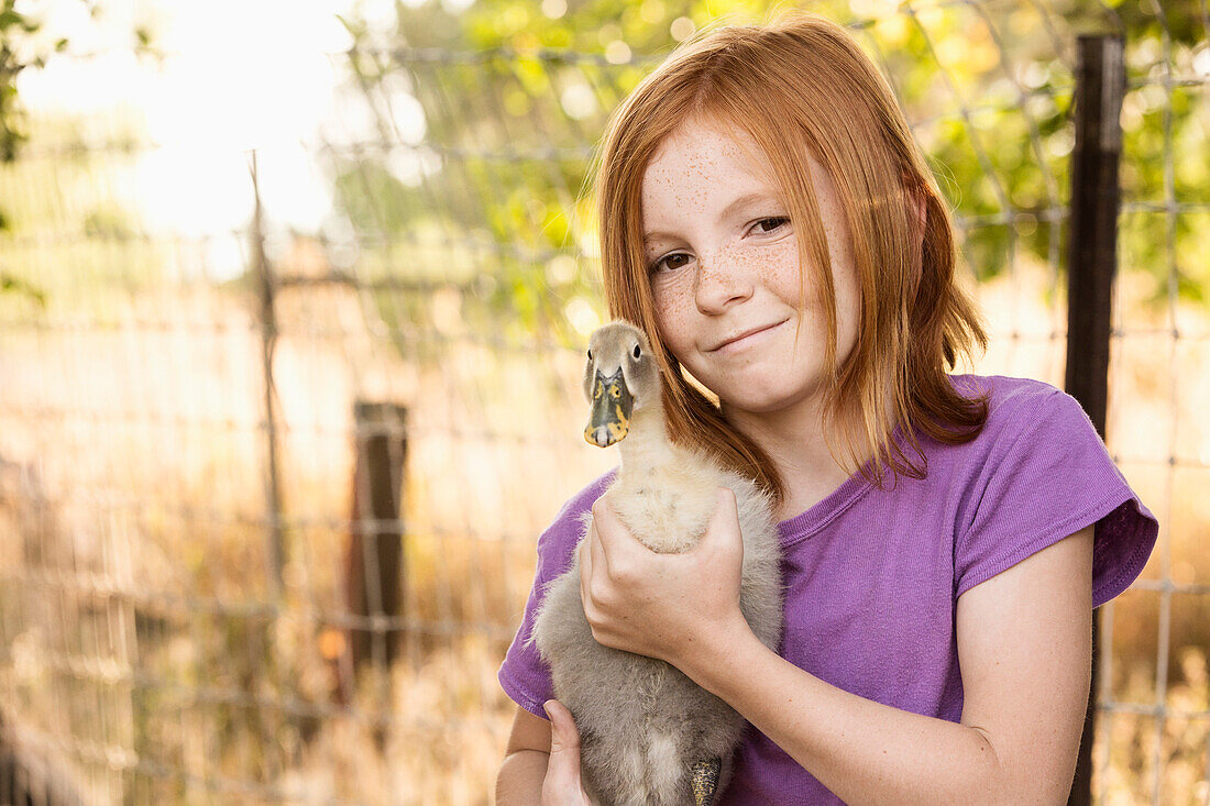 Girl holding duck on farm