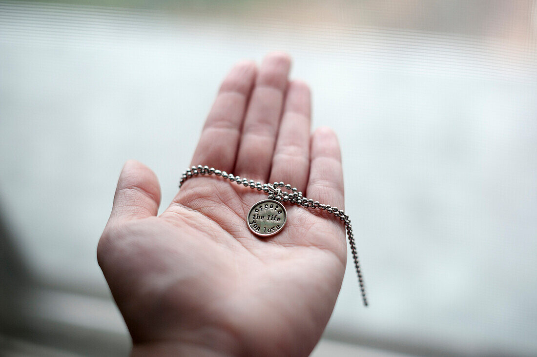 Hand of Caucasian woman holding necklace