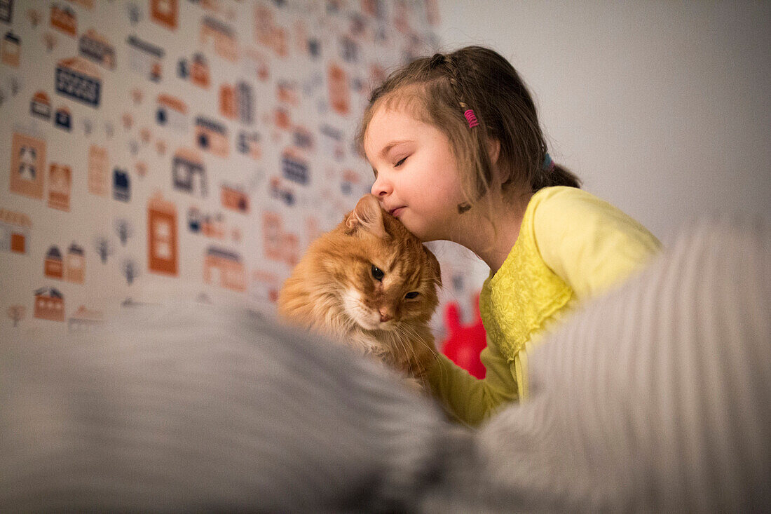 Caucasian girl hugging cat on bed