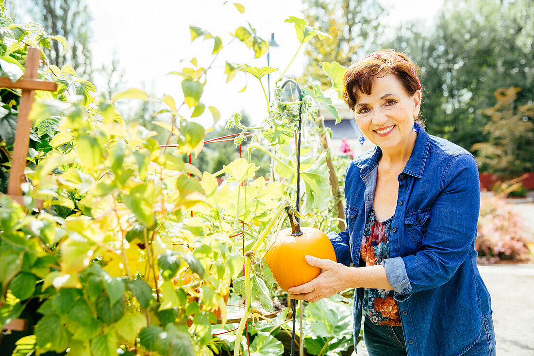 Kaukasische Frau hält Kürbis im Garten